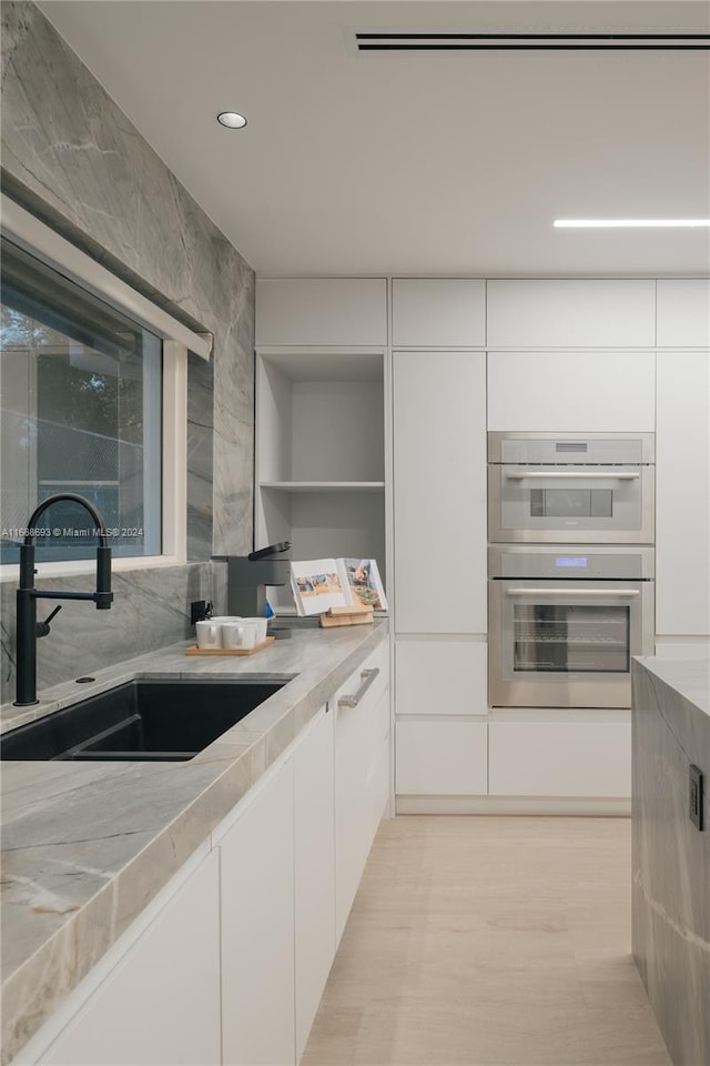 kitchen featuring sink, double oven, and white cabinets