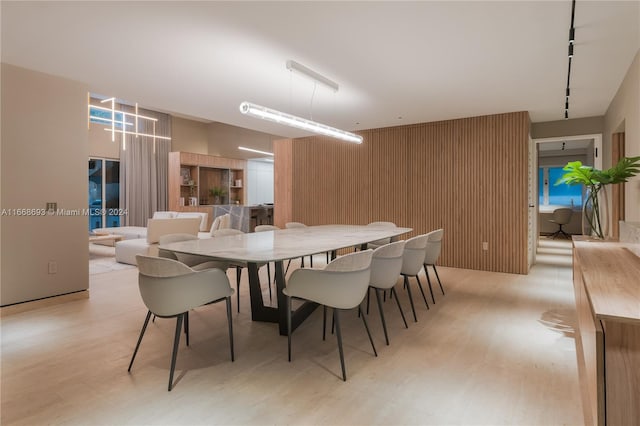 dining area with wooden walls and light wood-type flooring