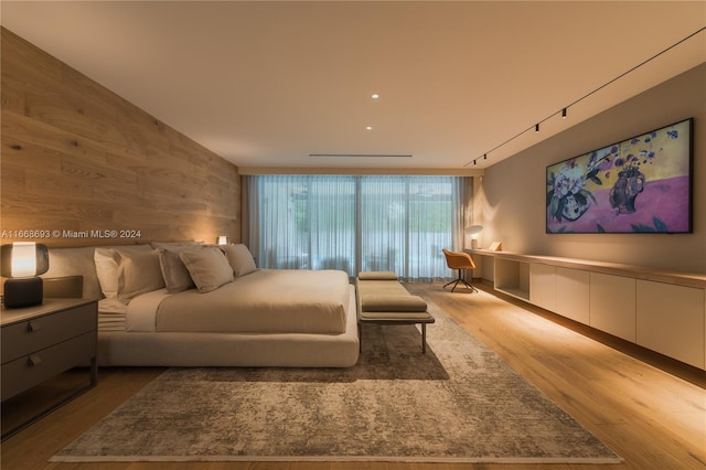 bedroom with wood-type flooring, track lighting, and floor to ceiling windows