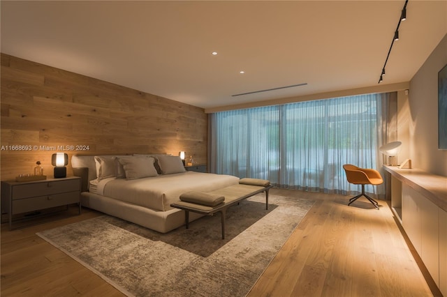 bedroom with wooden walls, light hardwood / wood-style flooring, and track lighting