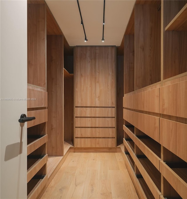 walk in closet with light hardwood / wood-style floors