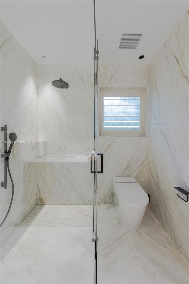 bathroom featuring a shower with door, toilet, and tile walls