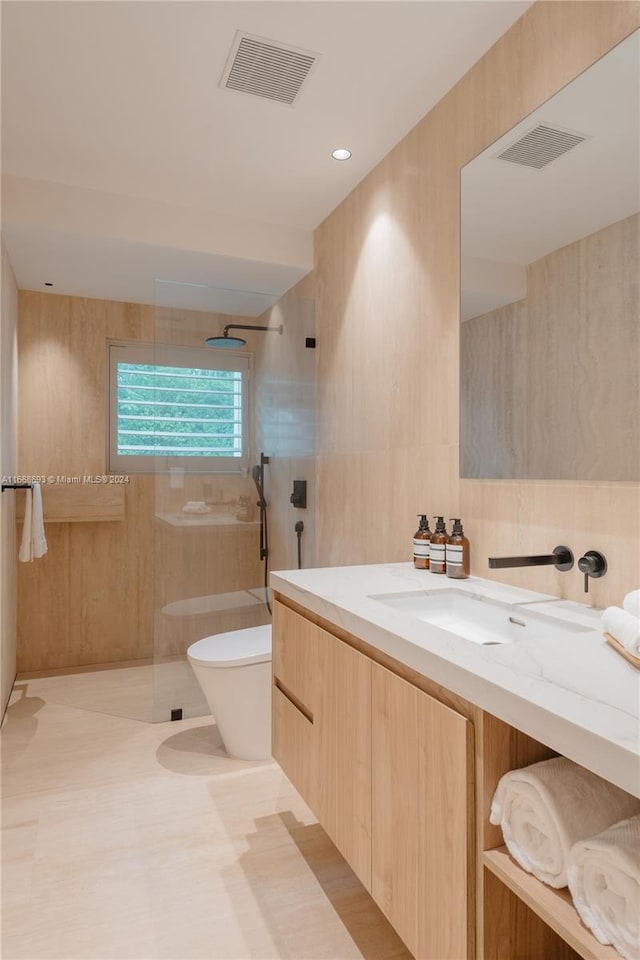 bathroom with toilet, vanity, tile walls, and tiled shower