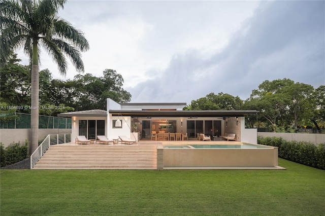 rear view of house with a wooden deck and a lawn