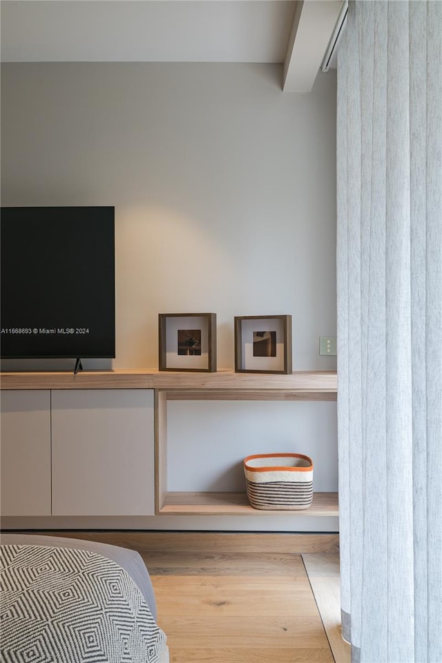 bedroom featuring light hardwood / wood-style floors and beamed ceiling