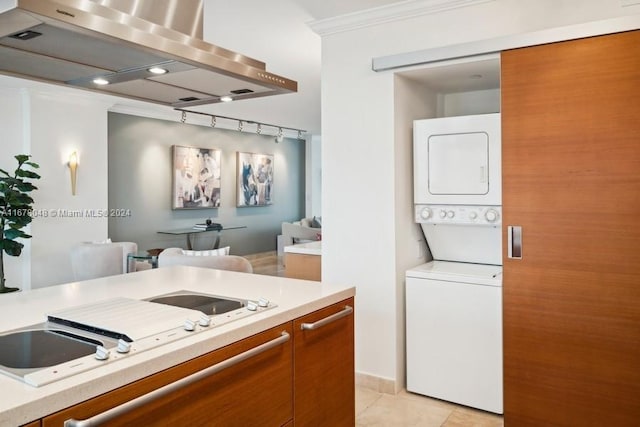 laundry area featuring crown molding, stacked washer and clothes dryer, and light tile patterned floors