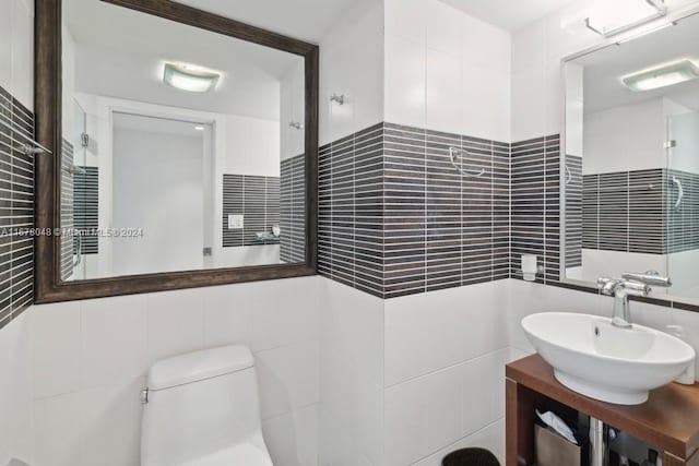 bathroom with toilet, vanity, and tile walls