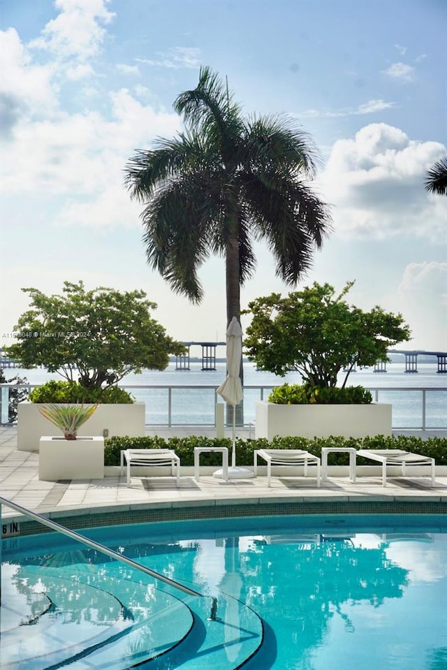 view of pool featuring a water view and a patio area