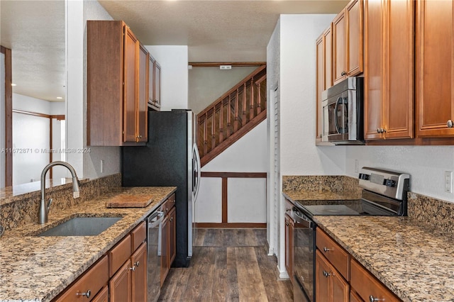 kitchen with sink, stone countertops, a textured ceiling, appliances with stainless steel finishes, and dark hardwood / wood-style flooring