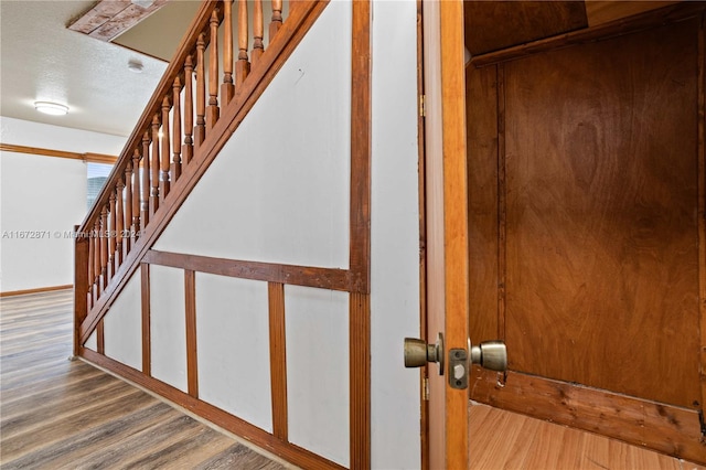 stairs with wood-type flooring and a textured ceiling