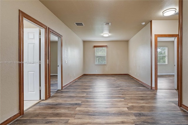 spare room with a textured ceiling, dark wood-type flooring, and a healthy amount of sunlight