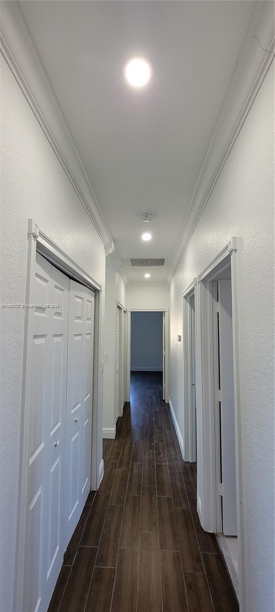 corridor featuring crown molding and dark hardwood / wood-style flooring