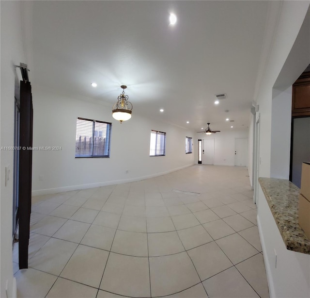 unfurnished room featuring ceiling fan, ornamental molding, and light tile patterned flooring