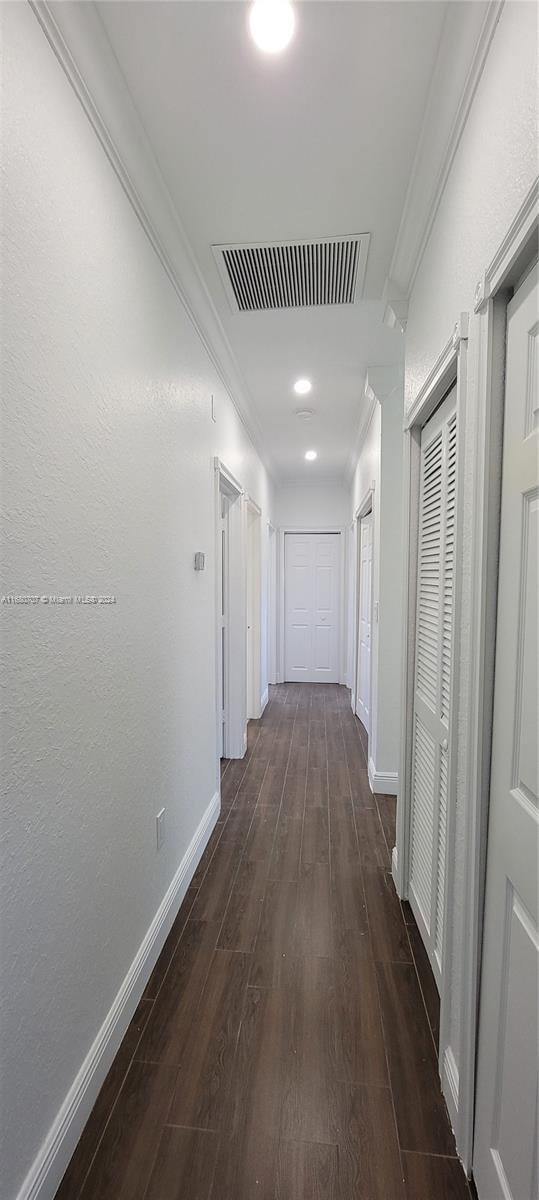 corridor with crown molding and dark wood-type flooring