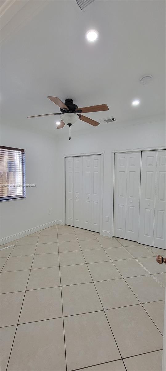 unfurnished bedroom featuring ceiling fan and light tile patterned flooring