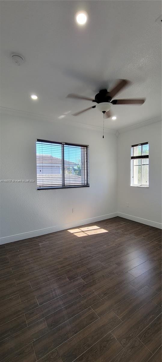 empty room with ceiling fan, crown molding, and dark wood-type flooring