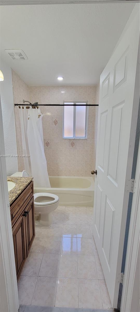 full bathroom featuring tile patterned flooring, shower / bath combo, vanity, and toilet