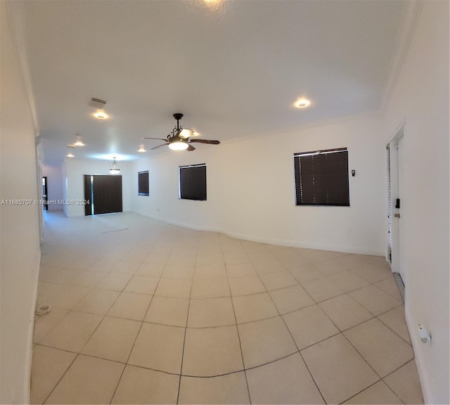 tiled empty room featuring ceiling fan and crown molding