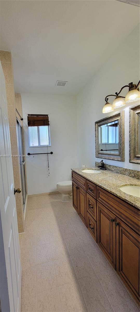 bathroom featuring tile patterned flooring, vanity, toilet, and a shower with door