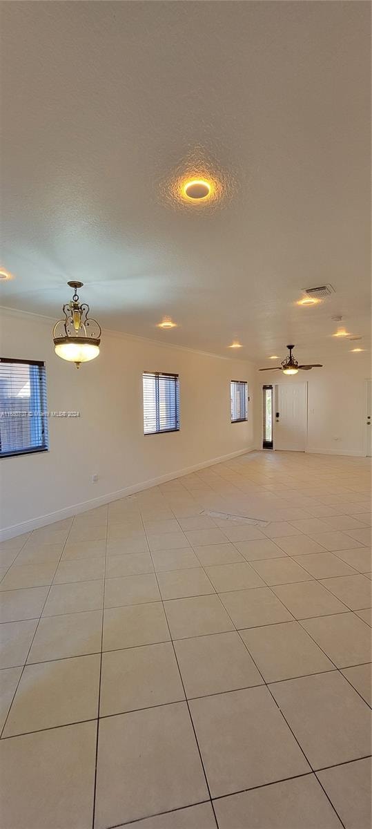 unfurnished room with ceiling fan, crown molding, light tile patterned floors, and a textured ceiling