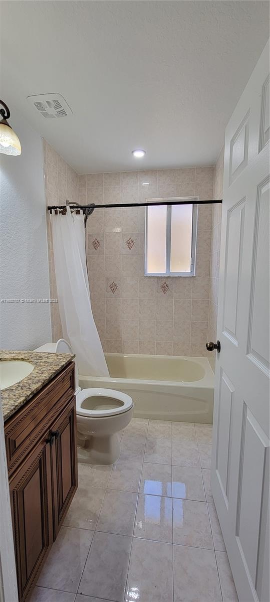 full bathroom featuring tile patterned floors, shower / tub combo with curtain, vanity, and toilet