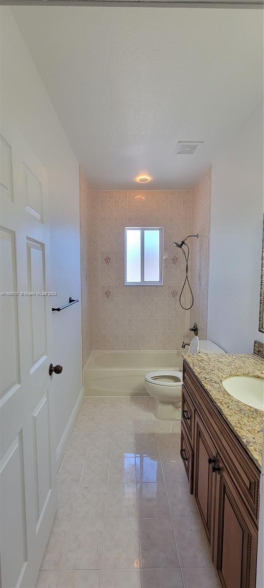 full bathroom with tiled shower / bath, tile patterned flooring, vanity, and toilet