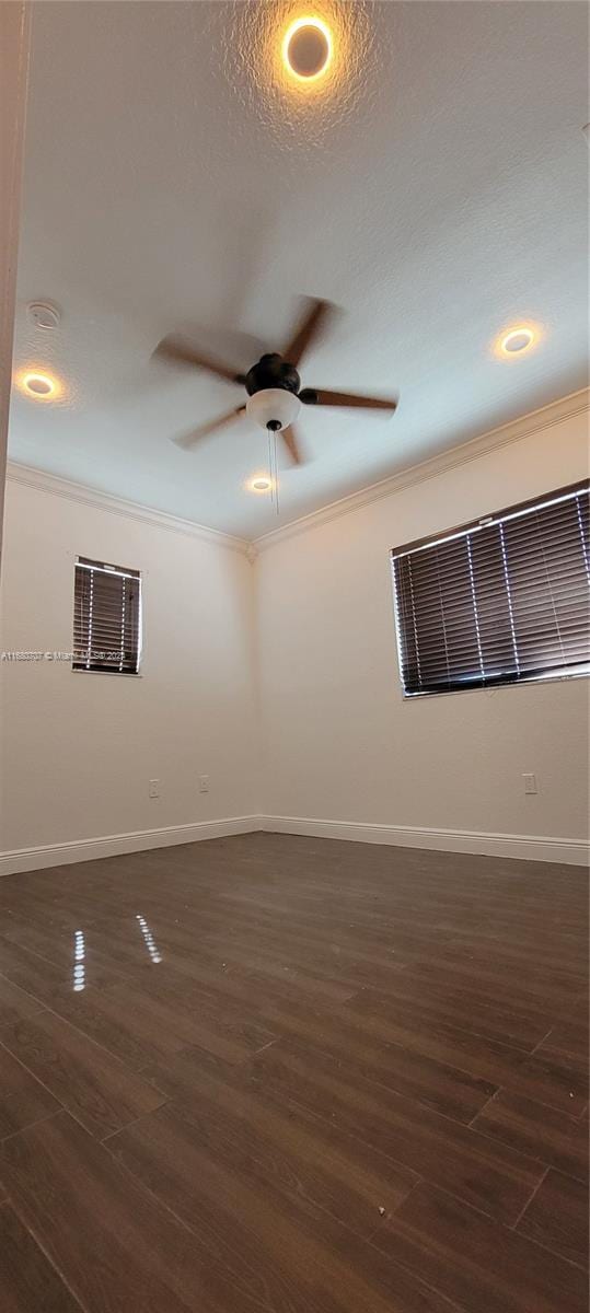 empty room with ornamental molding, a textured ceiling, ceiling fan, and dark wood-type flooring