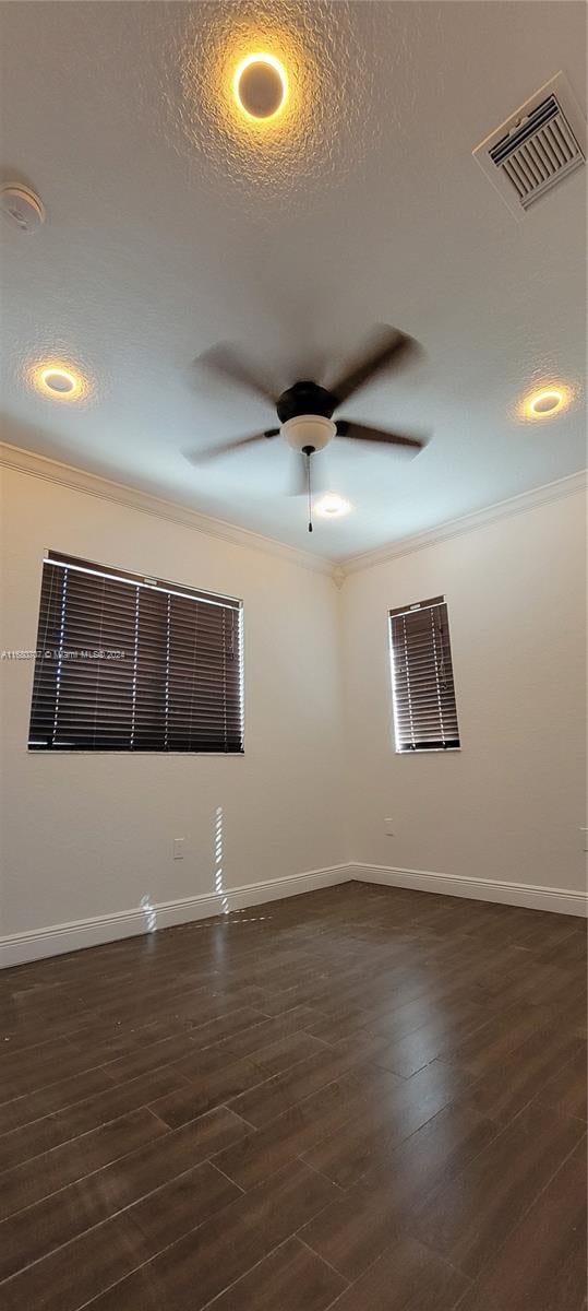 unfurnished room featuring a textured ceiling, ceiling fan, ornamental molding, and dark wood-type flooring