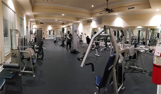 gym with ceiling fan and a tray ceiling