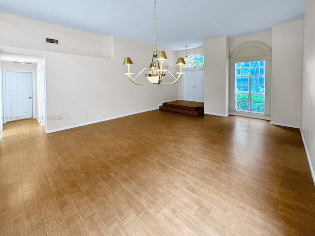 spare room with wood-type flooring and an inviting chandelier