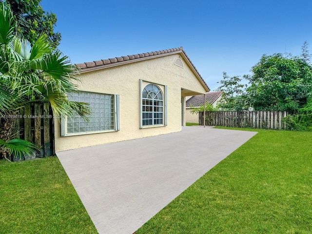 view of side of property with a patio and a lawn