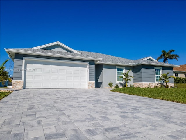 view of front facade featuring stone siding, decorative driveway, and a garage