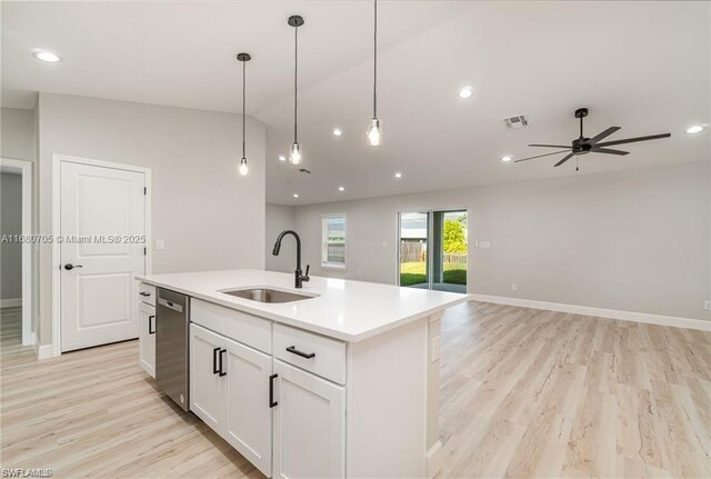 kitchen with sink, white cabinetry, stainless steel dishwasher, light hardwood / wood-style flooring, and a kitchen island with sink