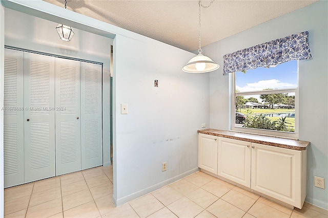 unfurnished dining area featuring a textured ceiling and light tile patterned flooring