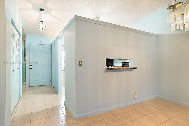 corridor featuring a textured ceiling and light tile patterned floors