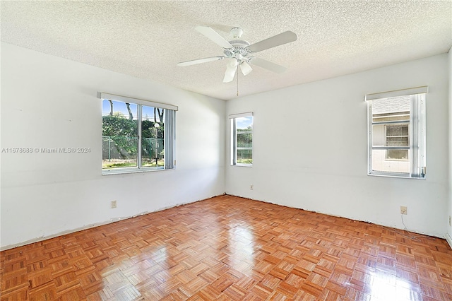 spare room with a textured ceiling, light parquet floors, and ceiling fan