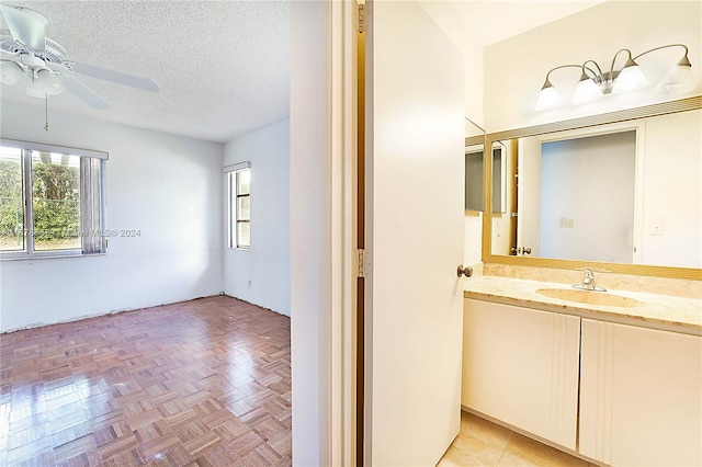 bathroom featuring vanity, ceiling fan, a textured ceiling, and parquet floors