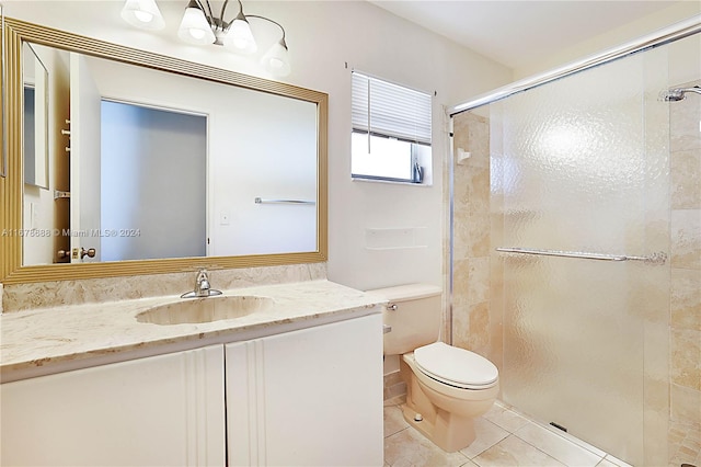 bathroom with toilet, walk in shower, vanity, and tile patterned flooring