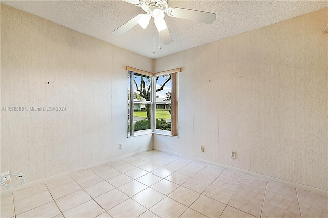 empty room featuring a textured ceiling, ceiling fan, and light tile patterned floors