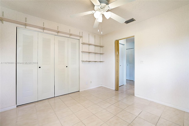 unfurnished bedroom with a closet, a textured ceiling, light tile patterned floors, and ceiling fan