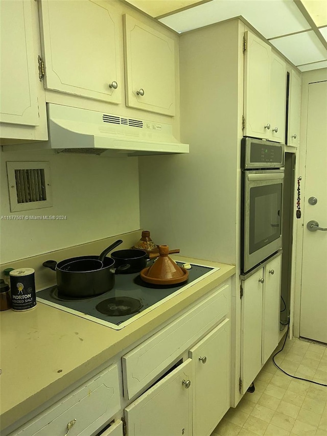 kitchen featuring stainless steel oven, white cabinetry, and electric stovetop