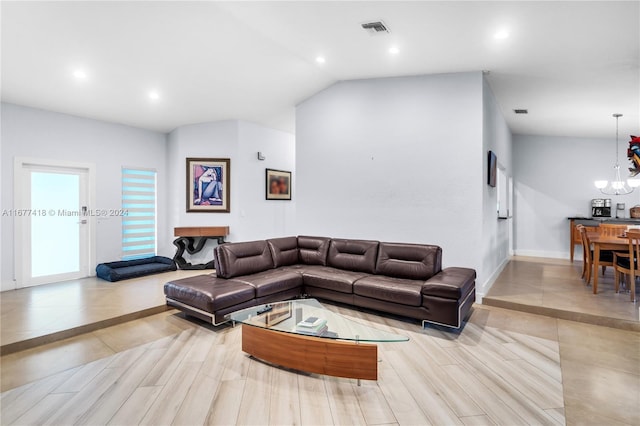 living room featuring light wood-type flooring, lofted ceiling, and a chandelier