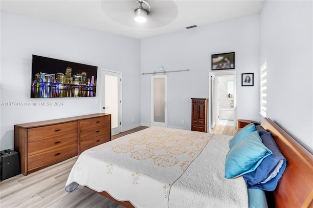 bedroom with connected bathroom, light hardwood / wood-style flooring, and ceiling fan