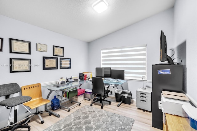 home office with a textured ceiling, light hardwood / wood-style flooring, and lofted ceiling