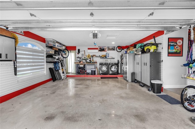 garage featuring a workshop area, stainless steel refrigerator, and washing machine and dryer