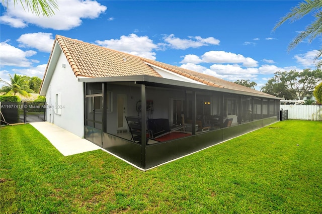 rear view of house featuring a lawn and a sunroom