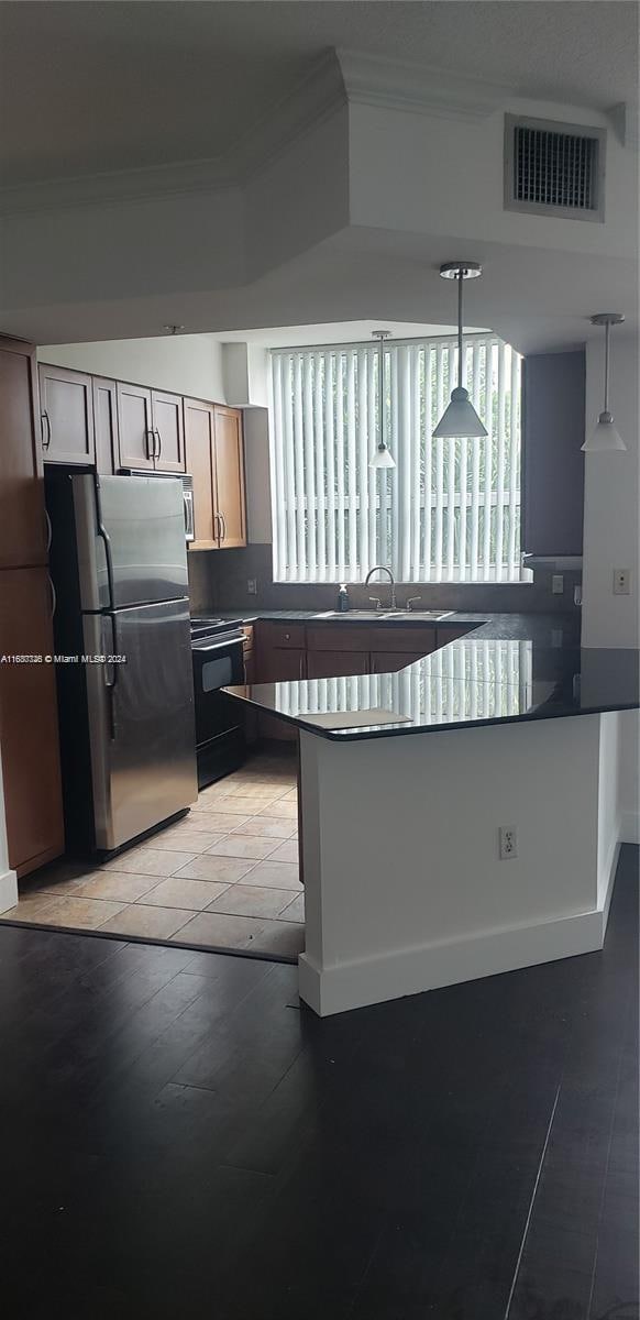 kitchen featuring light hardwood / wood-style floors, kitchen peninsula, stainless steel fridge, and decorative light fixtures