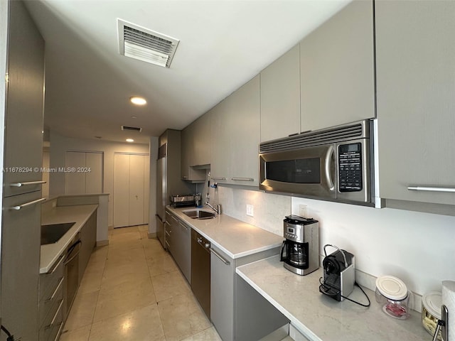 kitchen with tasteful backsplash, sink, light tile patterned floors, and appliances with stainless steel finishes