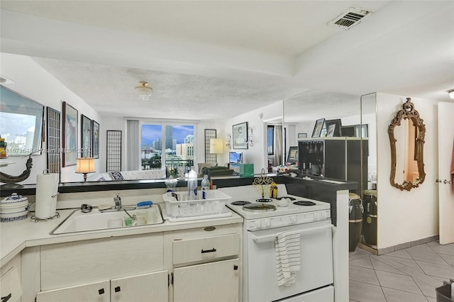 kitchen featuring electric stove, sink, light tile patterned floors, and a textured ceiling