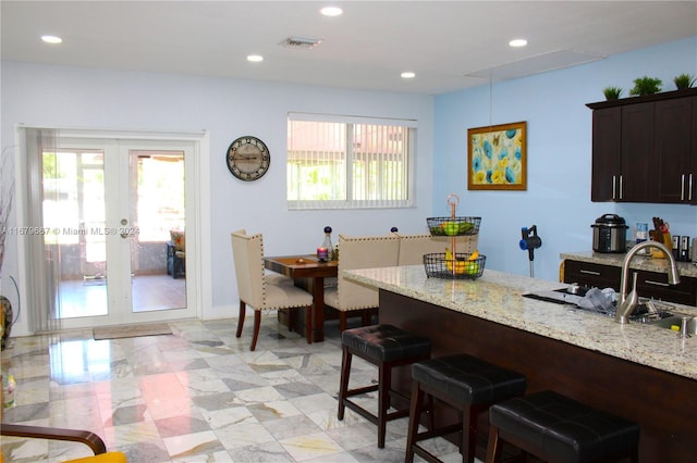 kitchen featuring light stone countertops, sink, a healthy amount of sunlight, and french doors